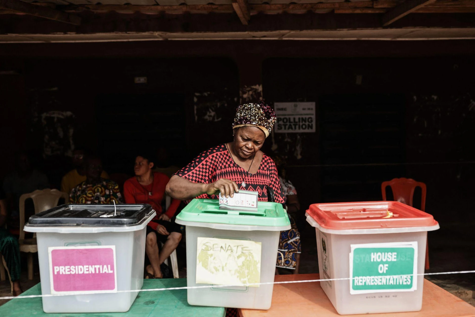 A woman casting her vote into presidential, senate and House of Representatives ballot boxes