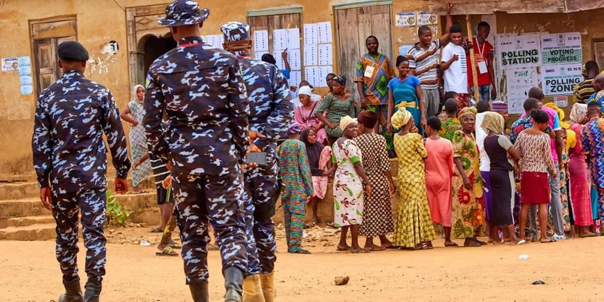 Voters queueing outside a polling station as security officers stand by